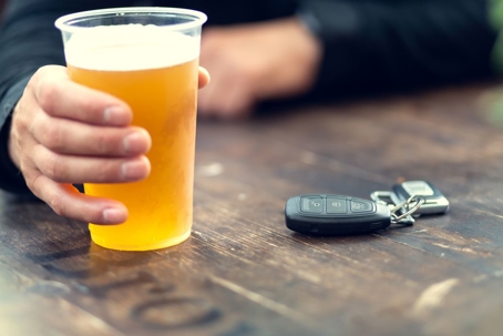 Man holding beer with car keys on table