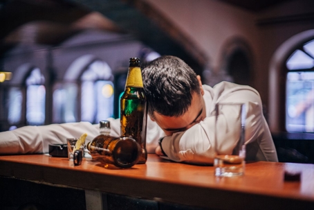 Man asleep at bar with bottles