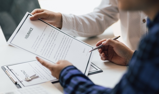 Man in office showing an insurance policy and pointing with a pen
